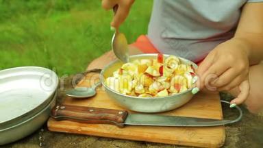一个女人用勺子在野餐上搅动水果沙拉。